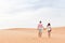 Young Man Woman Walking In Desert Couple Girl And Man Hold Hands Back Rear View Sand Dune Landscape