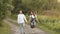 Young man and woman walking in a green meadow in the park holding hands in the summer. Romance, love, relationship