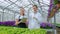 A young man and woman in white coats and black aprons, scientists, biologists or agronomists examine and analyze flowers