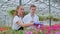 A young man and woman in white coats and black aprons, scientists, biologists or agronomists examine and analyze flowers