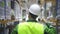 Young man worker putting helmet on head while walking in industrial warehouse.