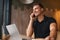 Young man working from cafe and talking on phone