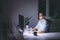 Young man working on computer at night in dark office