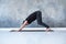 Young man working out, standing in yoga downward facing dog pose