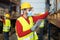 Young man working in warehouse doing inventory using digital tablet and loading delivery boxes plan while wearing face mask