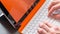 Young man is working on a white orange convertible laptop