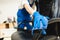 Young man in workwear and rubber gloves cleans the office chair with professional equipment.