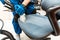 Young man in workwear and rubber gloves cleans the office chair with professional equipment.