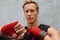 Young Man Wrapping Hand And Wrist With Boxing Tape Against Concrete Wall. Handsome Caucasian Sportsman.