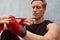 Young Man Wrapping Hand And Wrist With Boxing Tape Against Concrete Wall. Handsome Caucasian Sportsman.