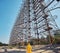 young man in yellow protective suit standing near military secret object antenna radar Duga in Chernobyl in Ukraine