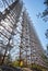 young man in yellow protective suit standing near military secret object antenna radar Duga in Chernobyl in Ukraine