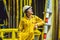 Young man in a yellow work uniform, glasses and helmet in industrial environment,oil Platform or liquefied gas plant