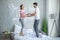 Young man and young pregnant woman in home wear jumping on the bed and feeling happy