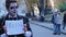 Young man in zombie suit holding free hugs sign in hands, smiling in camera