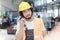 Young manual worker listening to walkie-talkie while looking up in metal industry