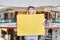 Young marketing woman is holding yellow blank signboard