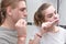 A young married couple brushes their teeth in the bathroom in the early morning