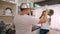 Young married couple doing a pretending casual fight with utensils and pans in kitchen at home. Funny husband and wife