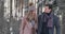 Young married couple in love walking in the winter forest. A man and a woman look at each other laughing and smiling in