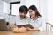 Young married couple showing happy smiling faces and using computers and notebooks to calculate household income and