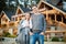 Young married couple standing outside their large wooden cottage in the woods.