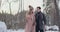 Young married couple walks through the winter forest. A man and a woman look at each other laughing and smiling in slow