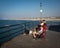 A young masked man sits in a group of fishermen on the Huntington Pier waiting for a bite