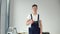 Young master in work uniform and with a set of tools stands on a white wall background