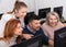 Young and mature business people grouped around computer monitor