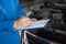 Young mechanic engineer taking a note on clipboard for examining