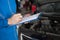 Young mechanic engineer taking a note on clipboard for examining