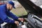 Young mechanic with flashlight fixing car