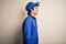 Young mechanic man wearing blue cap and uniform standing over isolated white background looking to side, relax profile pose with