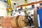 young mechanical engineering workers operate a machine for winding copper wire - manufacture of transformers in a factory