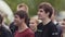 Young men group laughing and smiling watching performance at summer festival