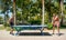 A young men plays table tennis without shirts in a park on a background of palms in a tourist city