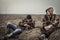 Young men with serene and peaceful expression in camouflage having rest in rural field relaxing on dry grass after long hunting da