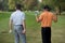 Young men standing in golf course with sticks, rear view