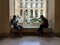 Young men study cell phones on window seat in Louvre