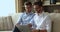 Young men twins spend time sitting on sofa using laptop