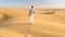 Young men walking in the desert of Dubai, Sand dunes of Dubai United Arab Emirates