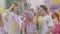 Young men and woman covered in holi festival colors dancing to music, slow-mo