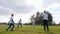 Young mens play with ball in slow motion at green grass on background blue sky, active games outdoors