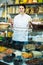 Young merchant is pouring on sweets into bag