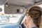 A young middle-aged woman does make-up paints her lips with lipstick in the car while looking into a small mirror in a visor