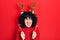 Young middle east woman wearing cute christmas reindeer horns smiling and laughing hard out loud because funny crazy joke