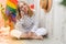 Young millennial hippie woman sitting on balcony using mobile phone. LGBTQ rainbow flag on background. Phone texting