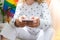 Young millennial hippie woman sitting on balcony using mobile phone. LGBTQ rainbow flag on background. Phone texting