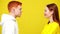 Young millennial redhead couple looking at each other at yellow background smiling. Side view of confident Caucasian man